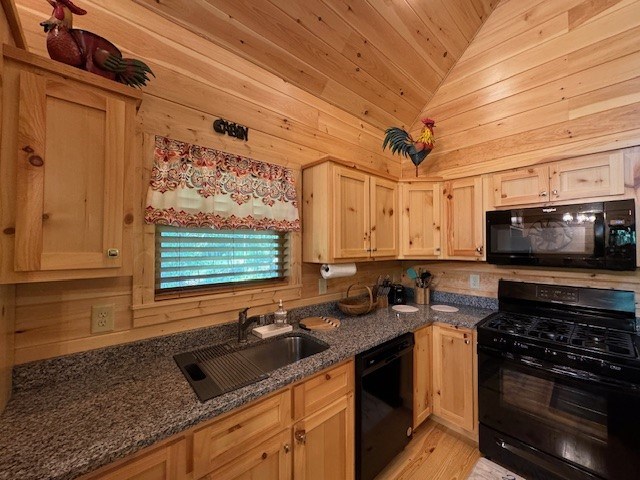 kitchen with black appliances, wooden walls, light hardwood / wood-style floors, and lofted ceiling