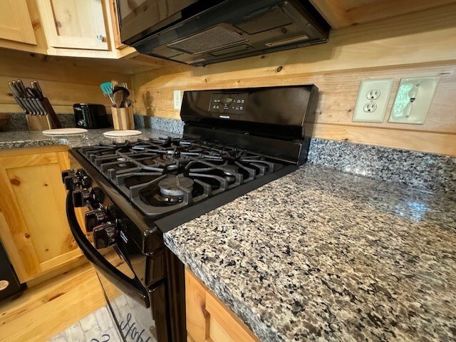 kitchen with dark stone countertops, light hardwood / wood-style floors, gas stove, and light brown cabinets