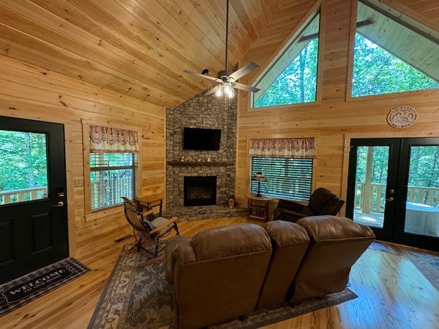 living room with wood ceiling, ceiling fan, french doors, a fireplace, and light wood-type flooring