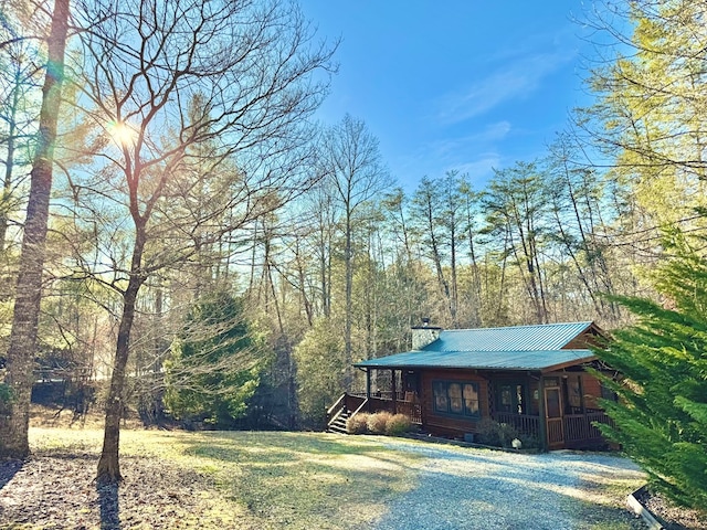 exterior space featuring metal roof, a porch, and a chimney