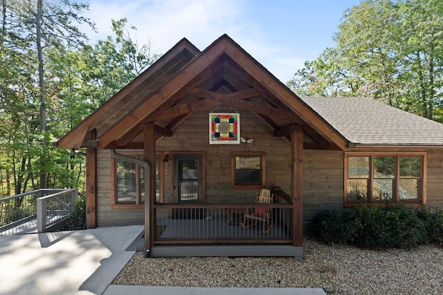 rustic home with covered porch and a shingled roof