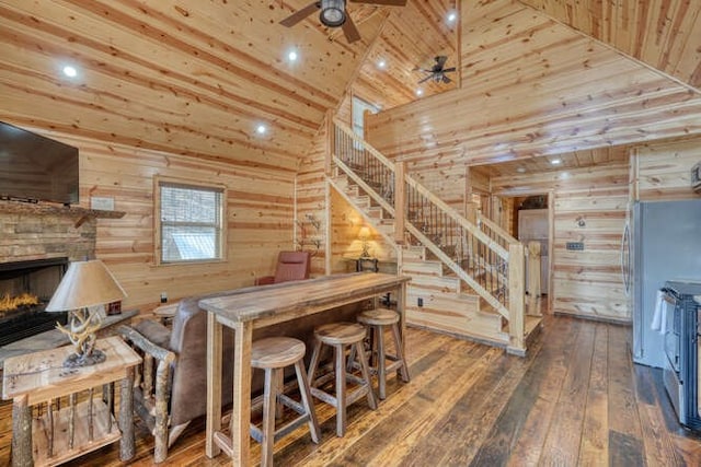 bar with high vaulted ceiling, hardwood / wood-style floors, wood walls, wood ceiling, and stairs