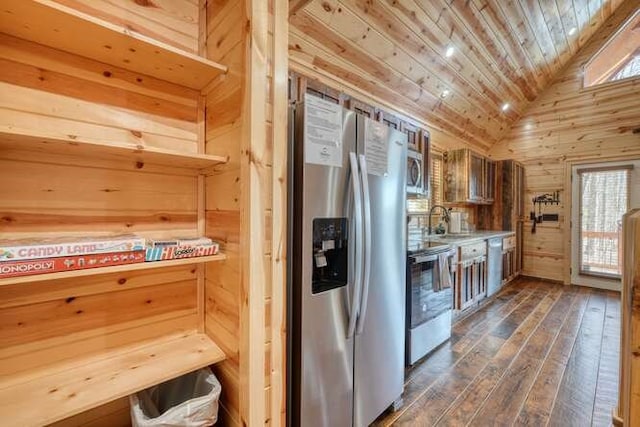 kitchen featuring dark wood-style flooring, vaulted ceiling, wood ceiling, wood walls, and appliances with stainless steel finishes