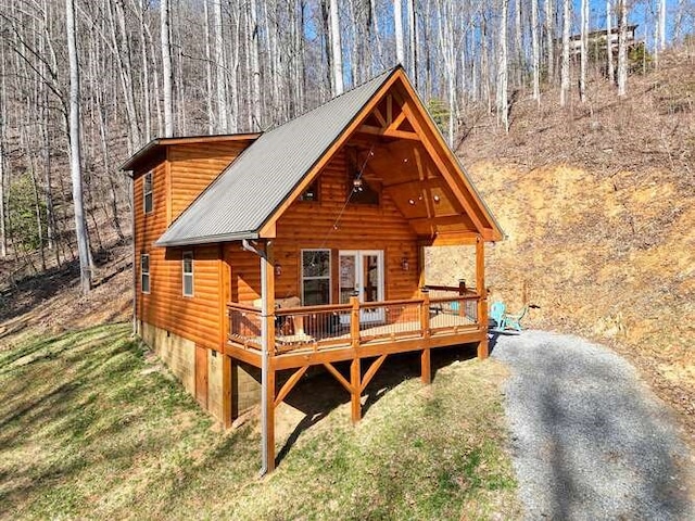 exterior space with ceiling fan, metal roof, a wooden deck, and a forest view