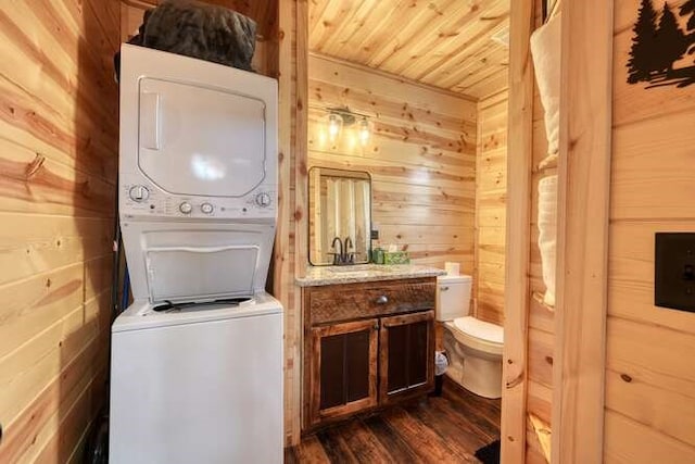 half bath with stacked washer and dryer, wood ceiling, wooden walls, and toilet