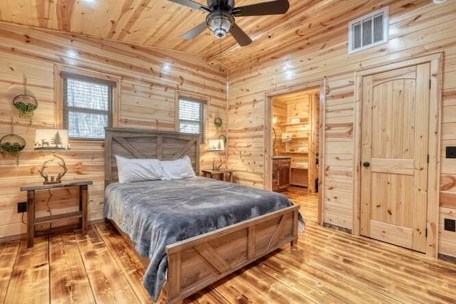 bedroom featuring visible vents, wood finished floors, wooden ceiling, wood walls, and lofted ceiling