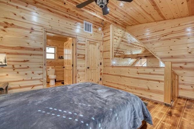 bedroom with visible vents, wood finished floors, wooden ceiling, and wood walls