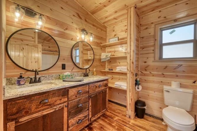 full bathroom with toilet, wood finished floors, wood walls, and a sink