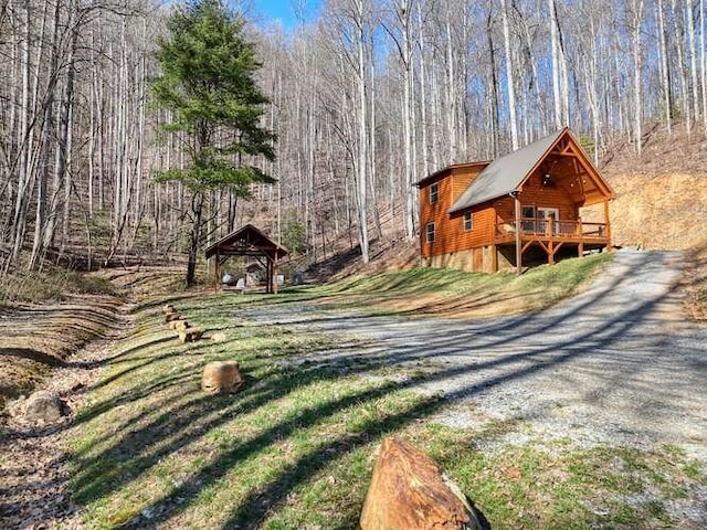 exterior space featuring a forest view and gravel driveway