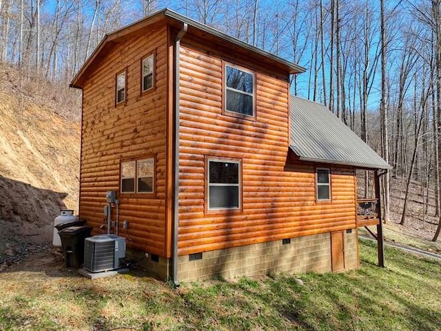 view of side of property featuring a yard, central AC, crawl space, faux log siding, and metal roof