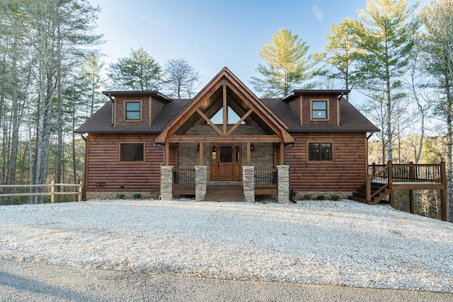 log-style house with covered porch, fence, and faux log siding