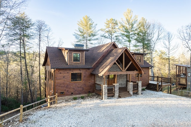 log-style house with covered porch, a shingled roof, a chimney, and log veneer siding