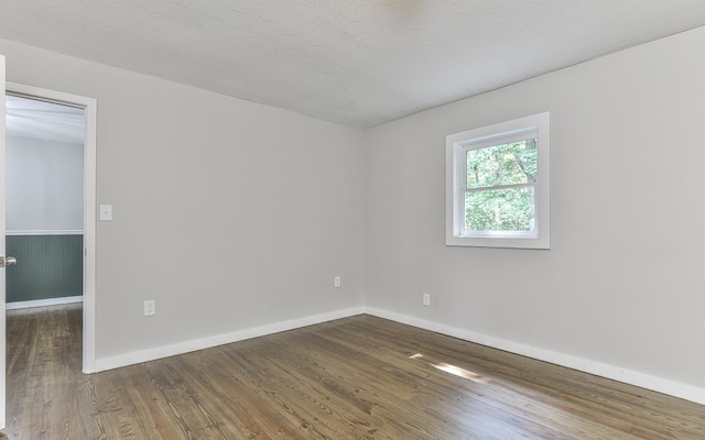 empty room featuring a textured ceiling and dark hardwood / wood-style floors