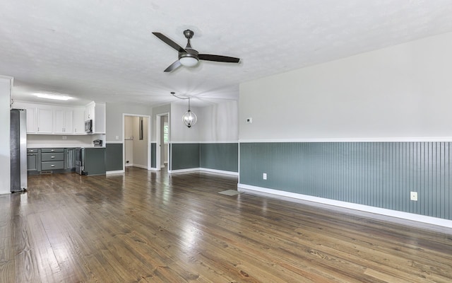 unfurnished living room with ceiling fan with notable chandelier and dark hardwood / wood-style flooring