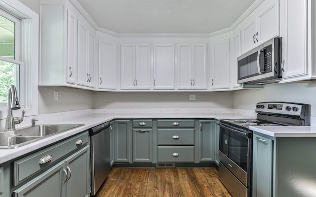 kitchen with dark wood-type flooring, appliances with stainless steel finishes, sink, white cabinets, and gray cabinets