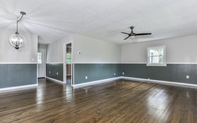 empty room featuring plenty of natural light, dark hardwood / wood-style floors, and ceiling fan with notable chandelier