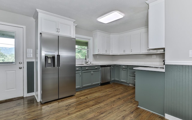 kitchen with appliances with stainless steel finishes, sink, white cabinets, and dark hardwood / wood-style flooring