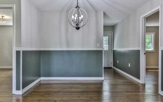 unfurnished room with an inviting chandelier and dark hardwood / wood-style floors