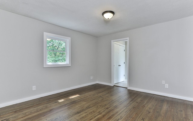 empty room with a textured ceiling and dark hardwood / wood-style flooring