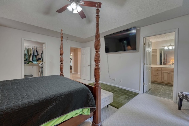 tiled bedroom featuring a textured ceiling, a spacious closet, ceiling fan, a closet, and ensuite bath