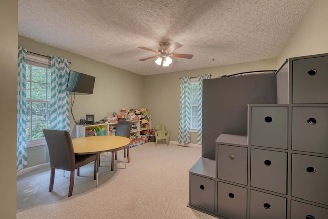 carpeted dining room with a textured ceiling and ceiling fan