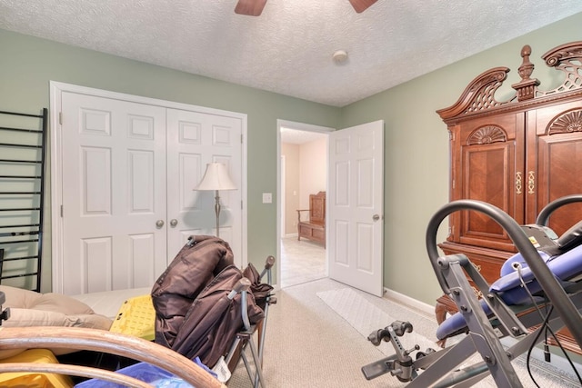 exercise area with light carpet, ceiling fan, and a textured ceiling