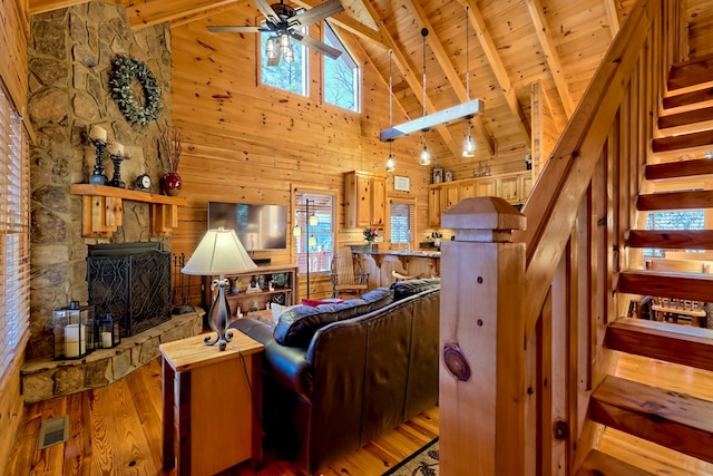 living area with beamed ceiling, light wood finished floors, stairway, and visible vents