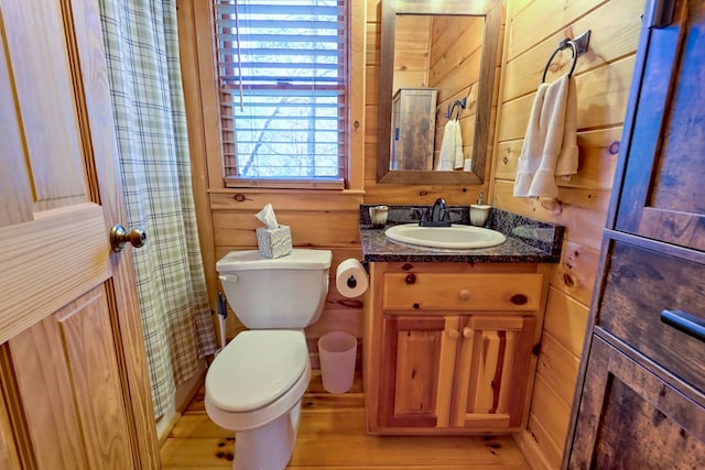 full bath with curtained shower, wood walls, vanity, and toilet