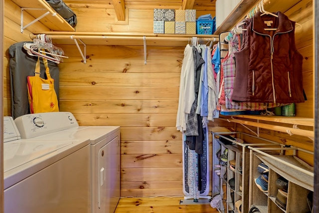 clothes washing area with wood walls and independent washer and dryer