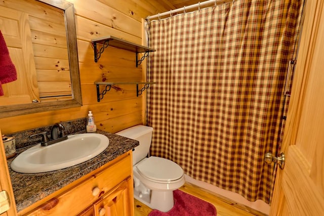 bathroom with toilet, wood walls, wood finished floors, and vanity