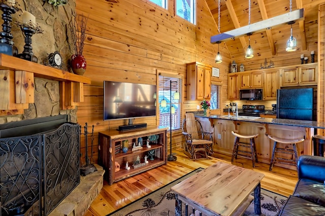 living area with a fireplace with raised hearth, wood ceiling, light wood-type flooring, wood walls, and high vaulted ceiling