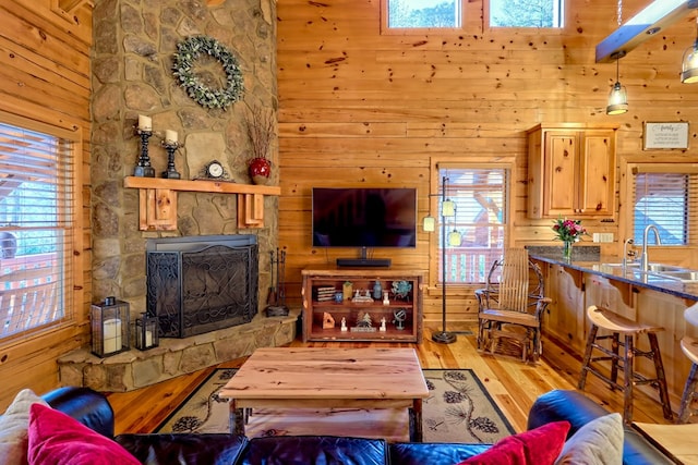 living room featuring a towering ceiling, light wood-style floors, wooden walls, and a fireplace