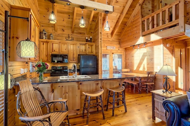 kitchen featuring wood ceiling, hanging light fixtures, wood walls, black appliances, and a sink