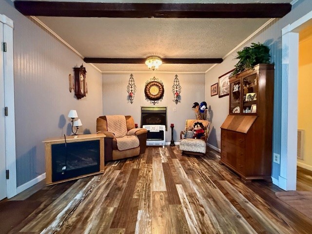 living area with dark wood finished floors, beam ceiling, and ornamental molding