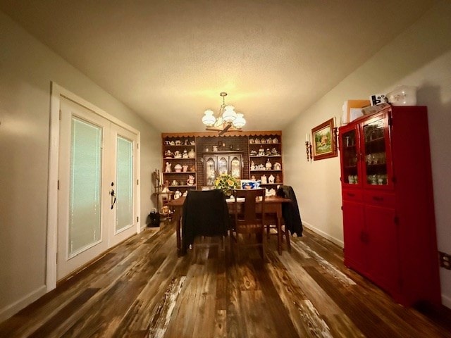 dining space with a textured ceiling, a chandelier, dark wood-style flooring, and baseboards