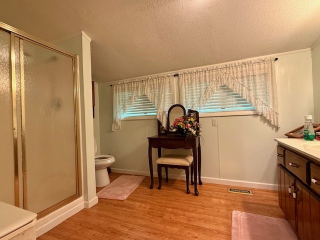 full bathroom featuring baseboards, visible vents, a shower stall, vanity, and wood finished floors