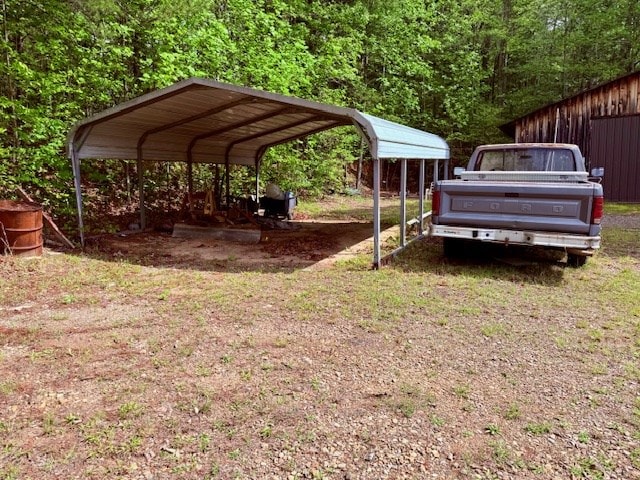 view of parking / parking lot featuring a detached carport and a forest view