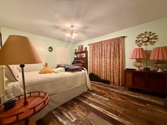 bedroom with a chandelier, a textured ceiling, and wood finished floors