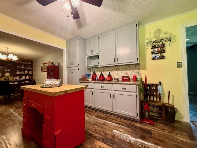 kitchen with wood counters, white cabinets, dark wood-style flooring, and ceiling fan with notable chandelier