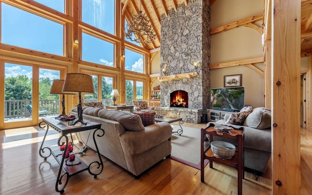 living room with beam ceiling, a stone fireplace, high vaulted ceiling, and light hardwood / wood-style floors