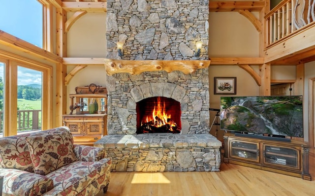 living room with a high ceiling, hardwood / wood-style floors, and a stone fireplace