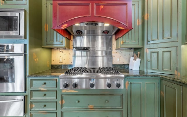 kitchen featuring tasteful backsplash, appliances with stainless steel finishes, custom exhaust hood, and dark stone countertops