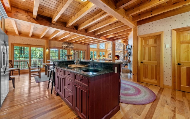 kitchen with sink, wood ceiling, beamed ceiling, light hardwood / wood-style floors, and a center island