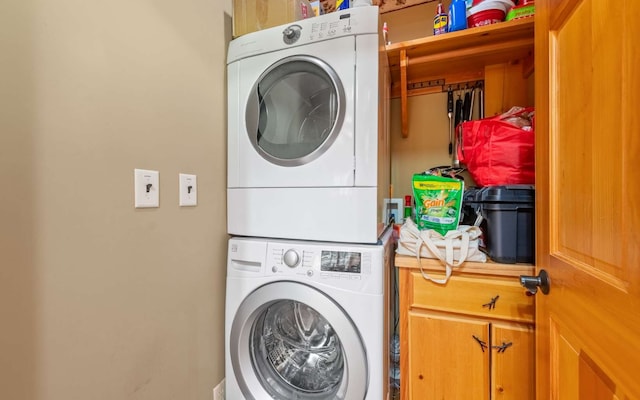 laundry room with stacked washer and dryer, cabinets, and hookup for a washing machine