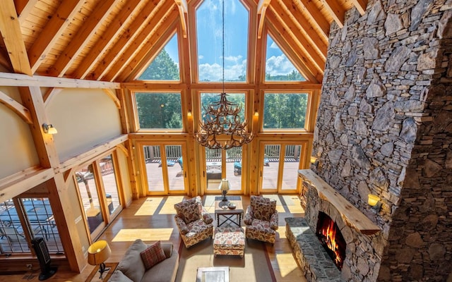 interior space with wooden ceiling, a notable chandelier, vaulted ceiling with beams, and a stone fireplace