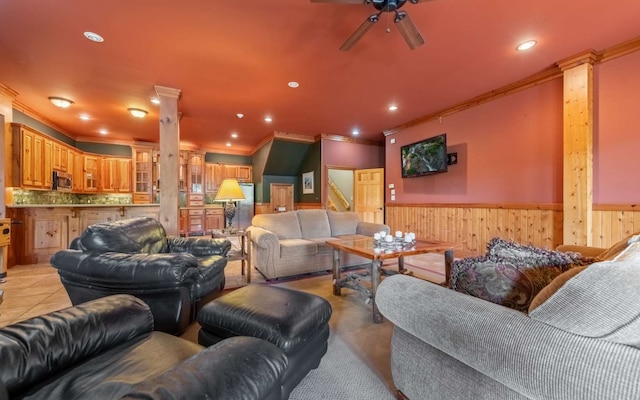 living room featuring ceiling fan, ornamental molding, light tile flooring, and ornate columns