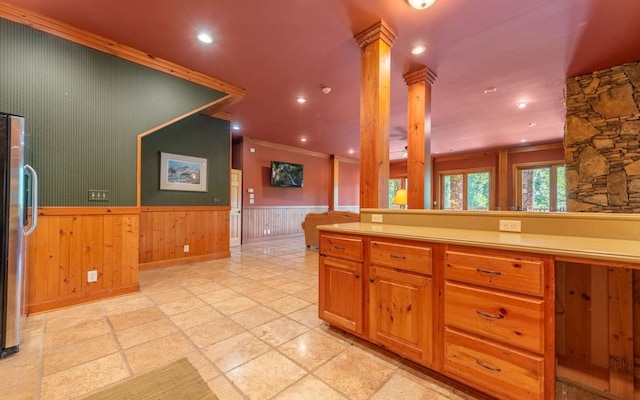 kitchen featuring light tile flooring, ornamental molding, ornate columns, and stainless steel fridge