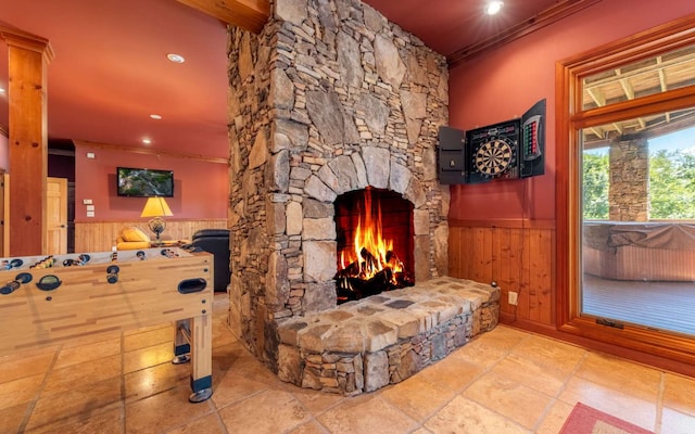 interior space with light tile flooring, crown molding, and a stone fireplace