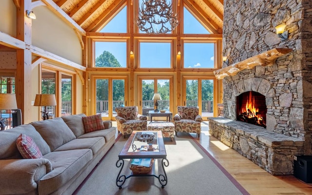 living room featuring beamed ceiling, wood-type flooring, a fireplace, high vaulted ceiling, and an inviting chandelier