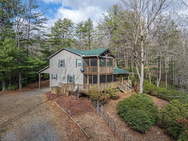 back of property with a sunroom, a carport, and a deck